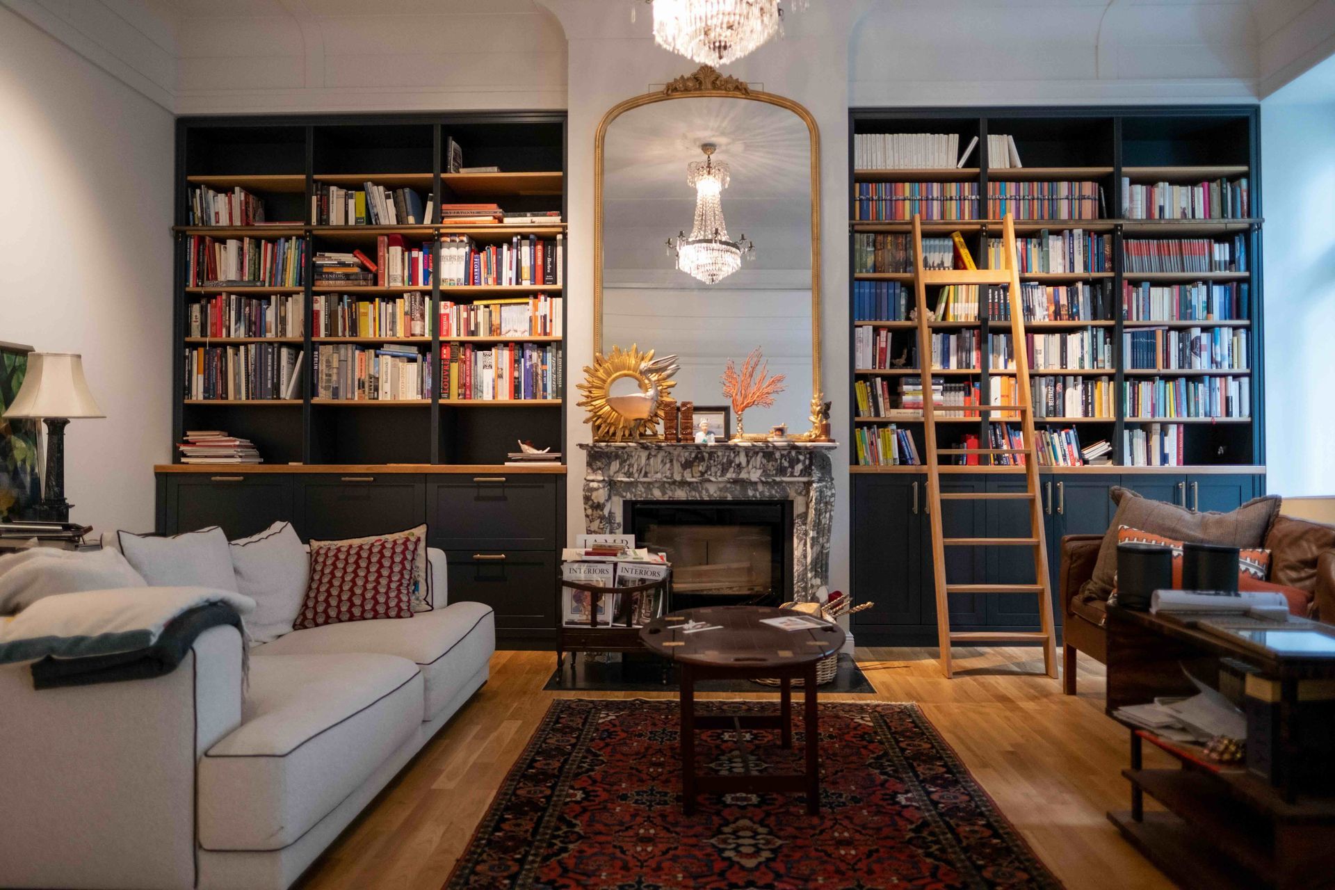 Wohnzimmer mit maßgefertigter Bibliothek, Kaminverkleidung und Messingdetails – ROY Design Altbauprojekt Berlin