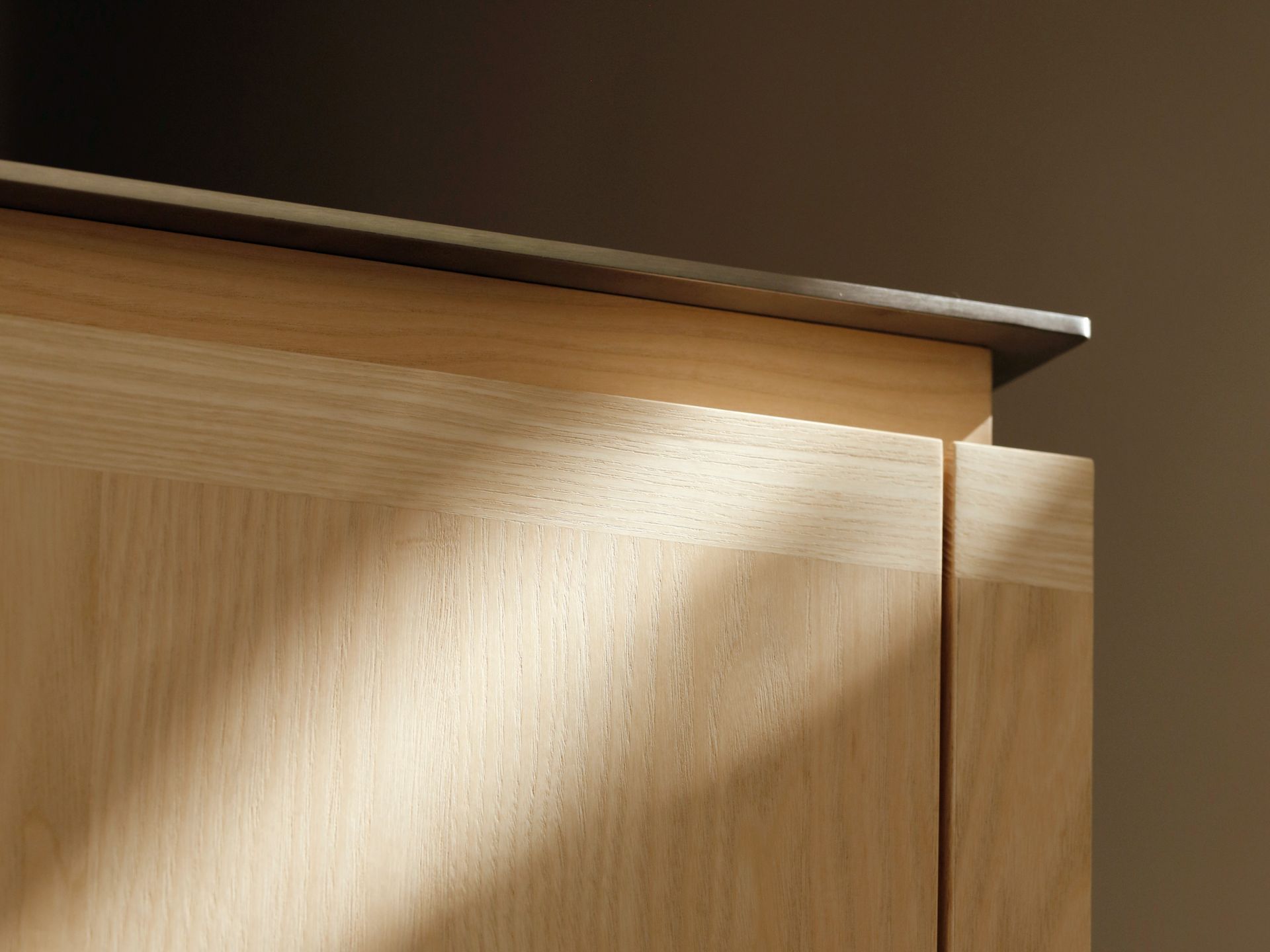 Detailansicht Edelstahl-Arbeitsplatte mit präziser Kante auf hellen Massivholzfronten – ROY Design Zehlendorf