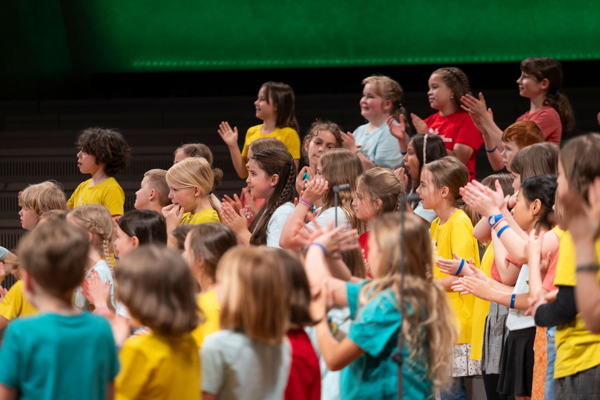 Der Jugendchor sitzend beim Singen mit Simon Halsey vorne stehend als Dirigent.