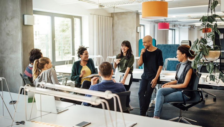 Grupo de personas de distintas etnias reunidos soriendo y charlando sobre Bienestar