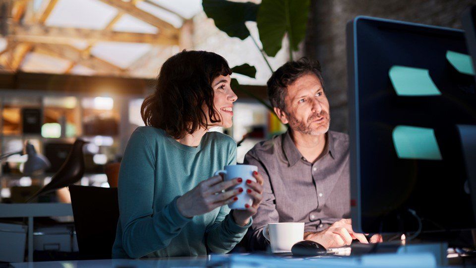 Hombre y mujer sonriendo viendo en el ordenador las distintas opciones de formación
