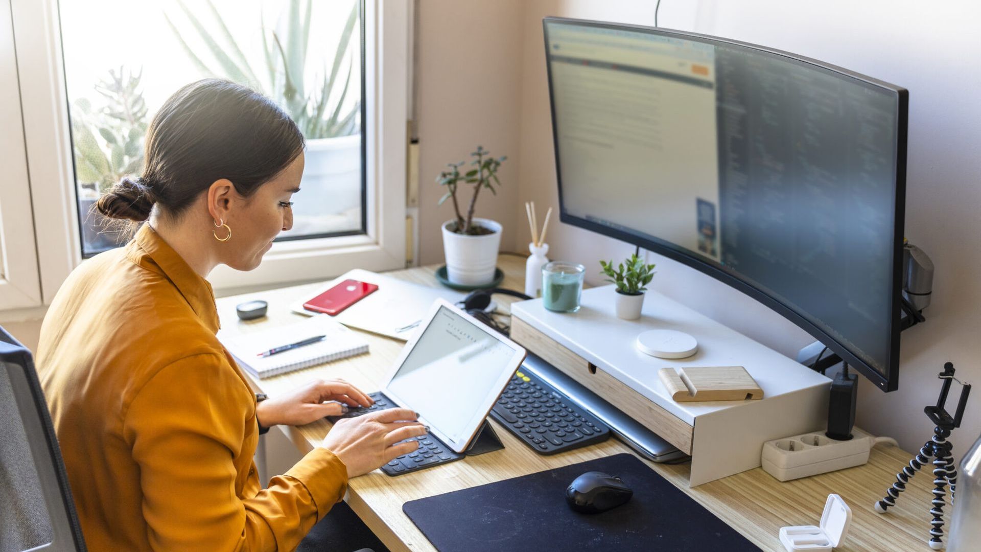 Mujer trabajando en casa delante del ordenaror y la tablet