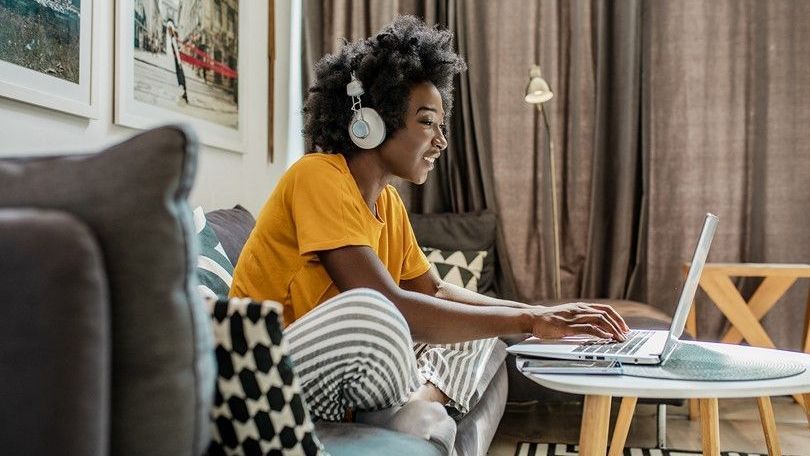 Joven negra con cascos visualizando su portátil