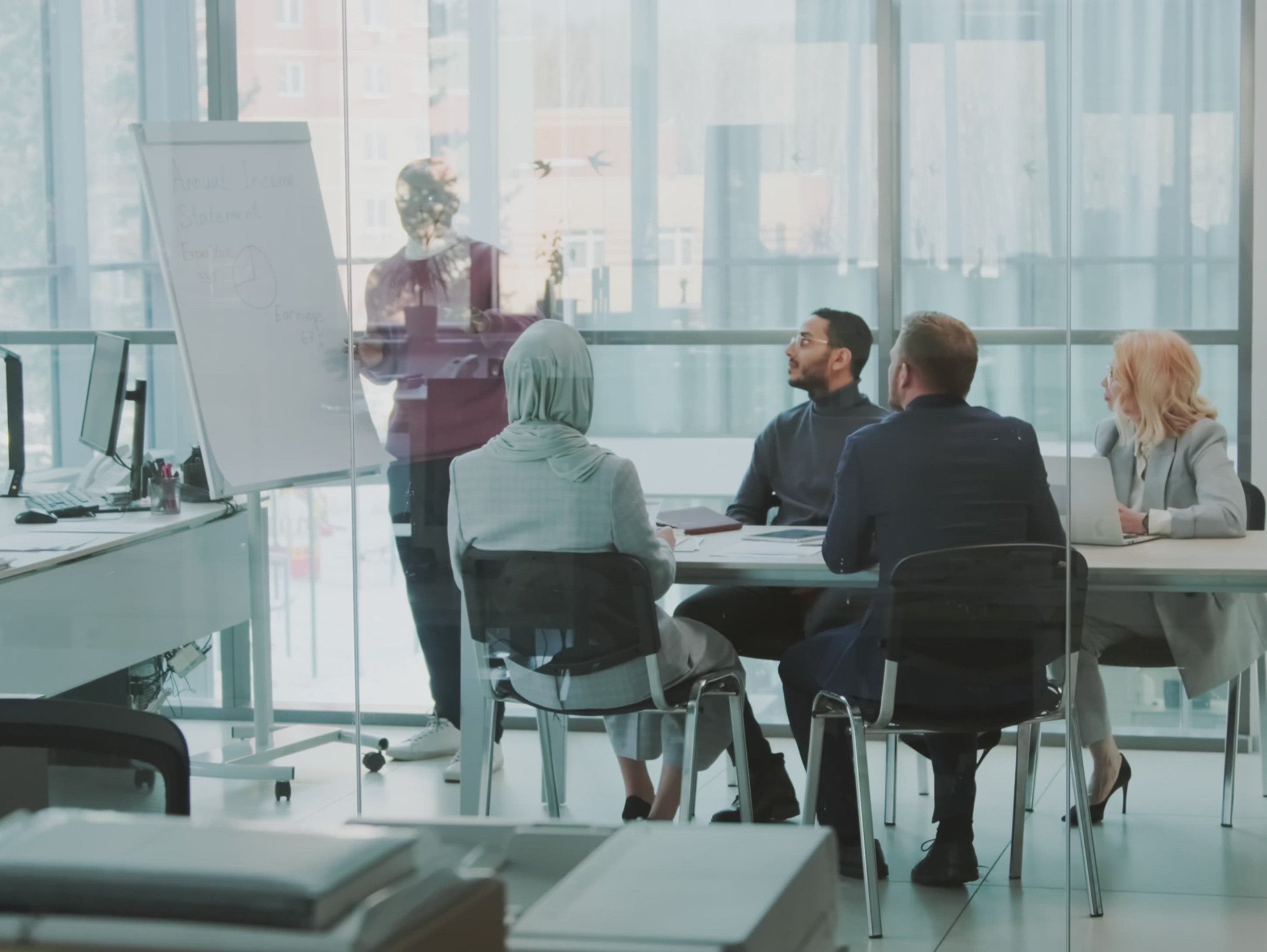Profesional haciendo una exposición para tres compañeros con el apoyo de un papelografo sobre Diversidad