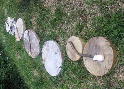 Schamanentrommeln liegen aneinandergereiht, in der grünen Wiese.