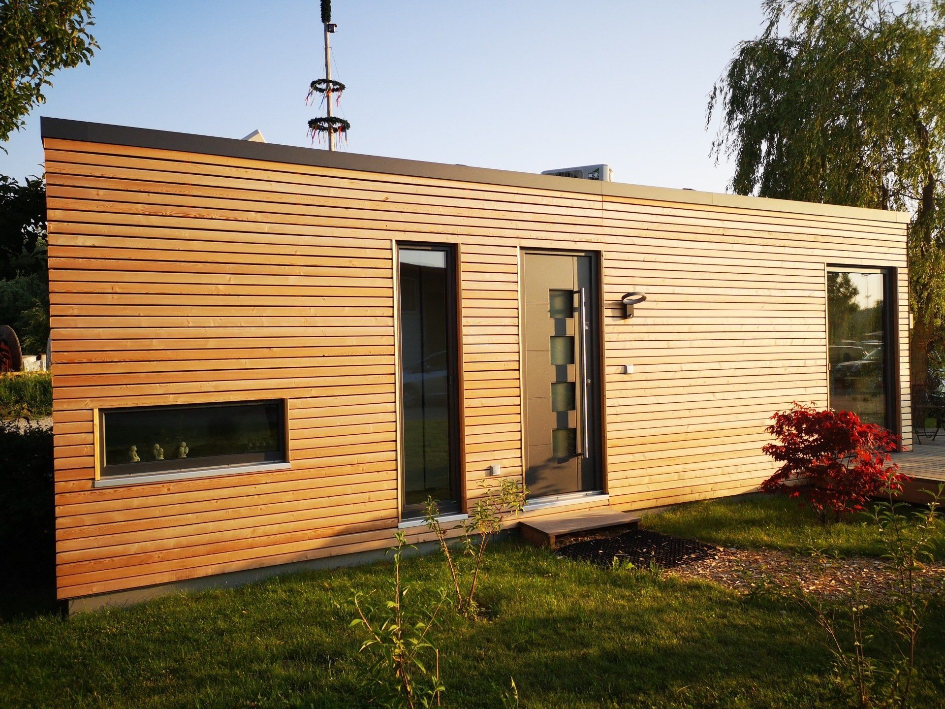 Die Lärche-Außenfassade des QUBEs. Minimalistisch und formschön durchbrochendurch geometrische Ausschnitte der Fenster und Türen.