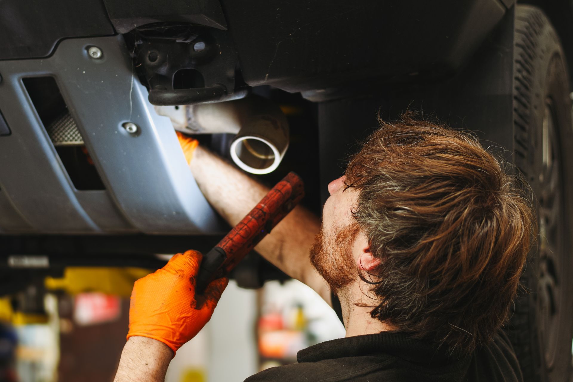 Technician holding a torch to inspect the underside of an INEOS Grenadier.