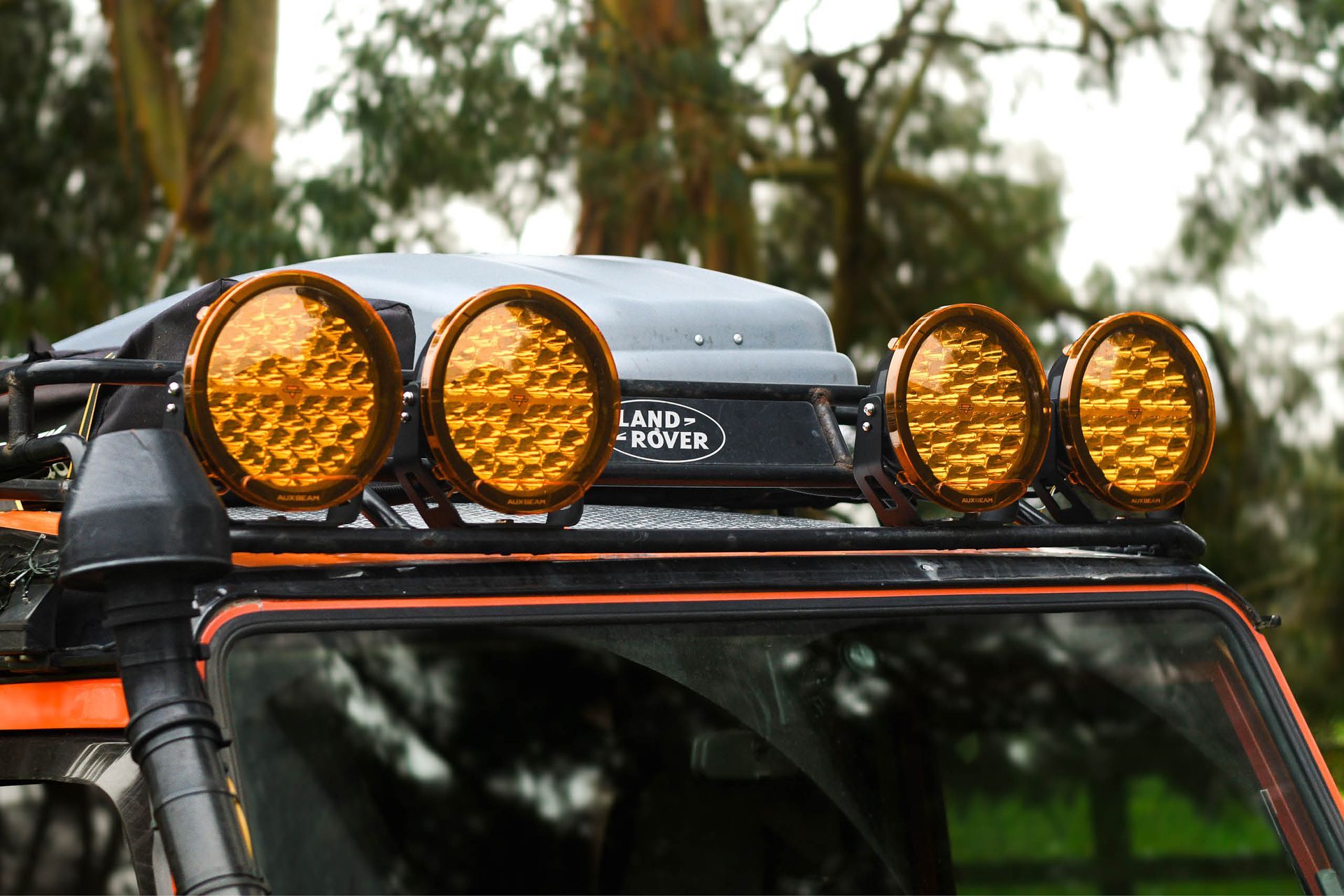 Orange Defender with auxiliary roof spotlights prepared for off-road use