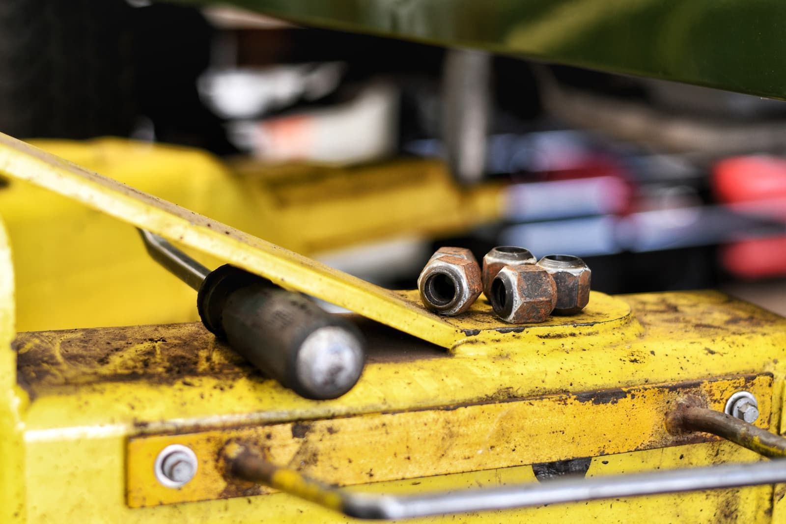 Nuts and a screwdriver lying on a yellow workshop surface.