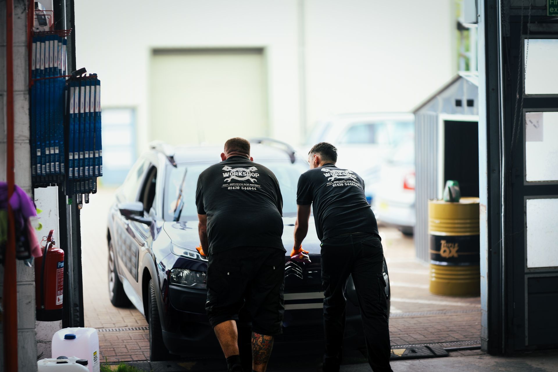Two technicians pushing a car at The Workshop, Alton.