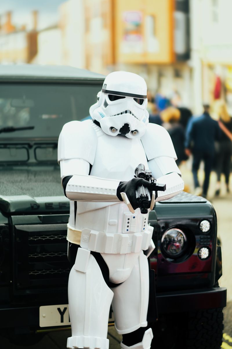 Star Wars Stormtrooper pointing a blaster in-front of a green Land Rover Defender 110