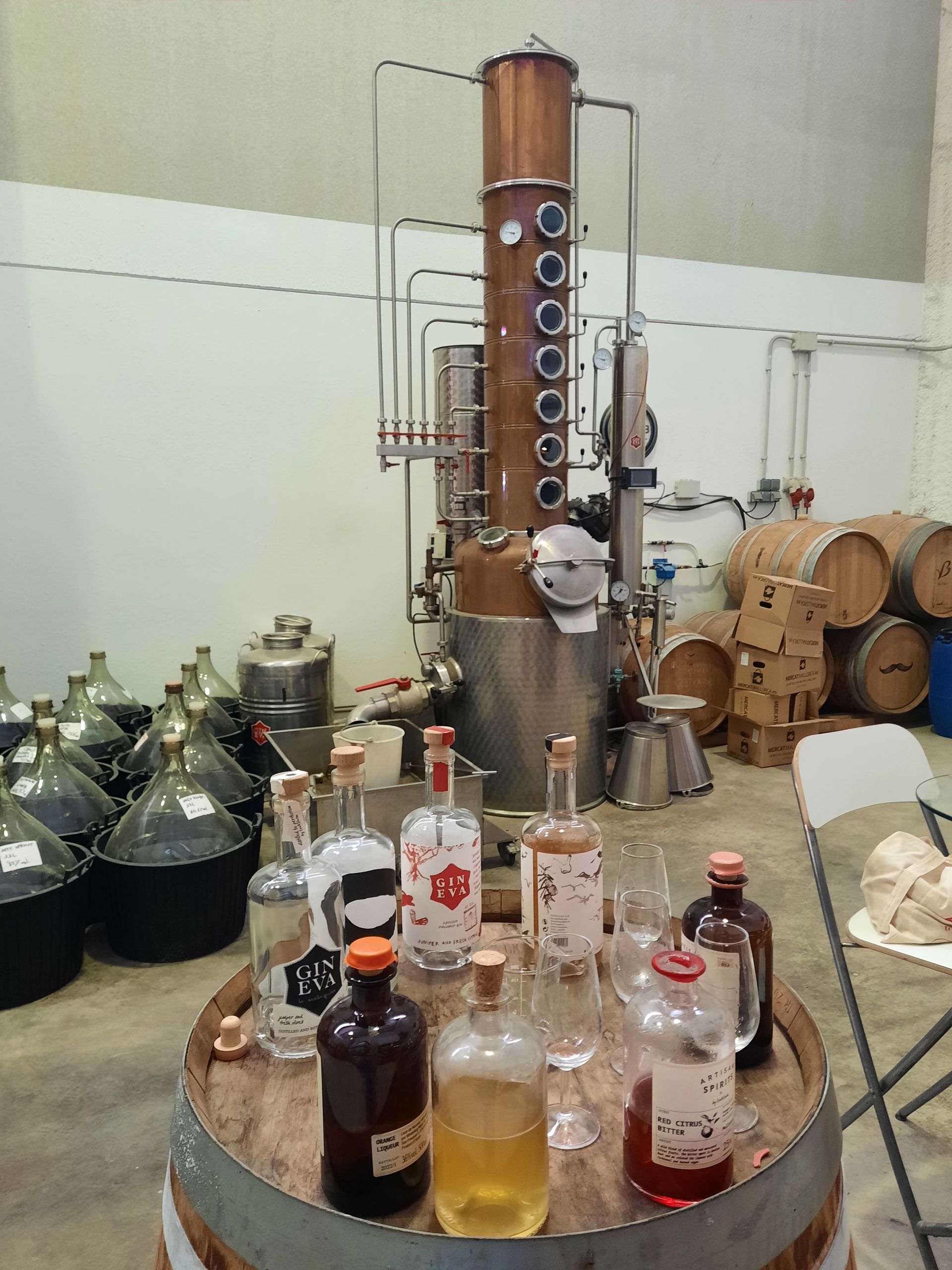 Gin Destillerie mit Weinfässern, Kupferkolben und Gin Flaschen