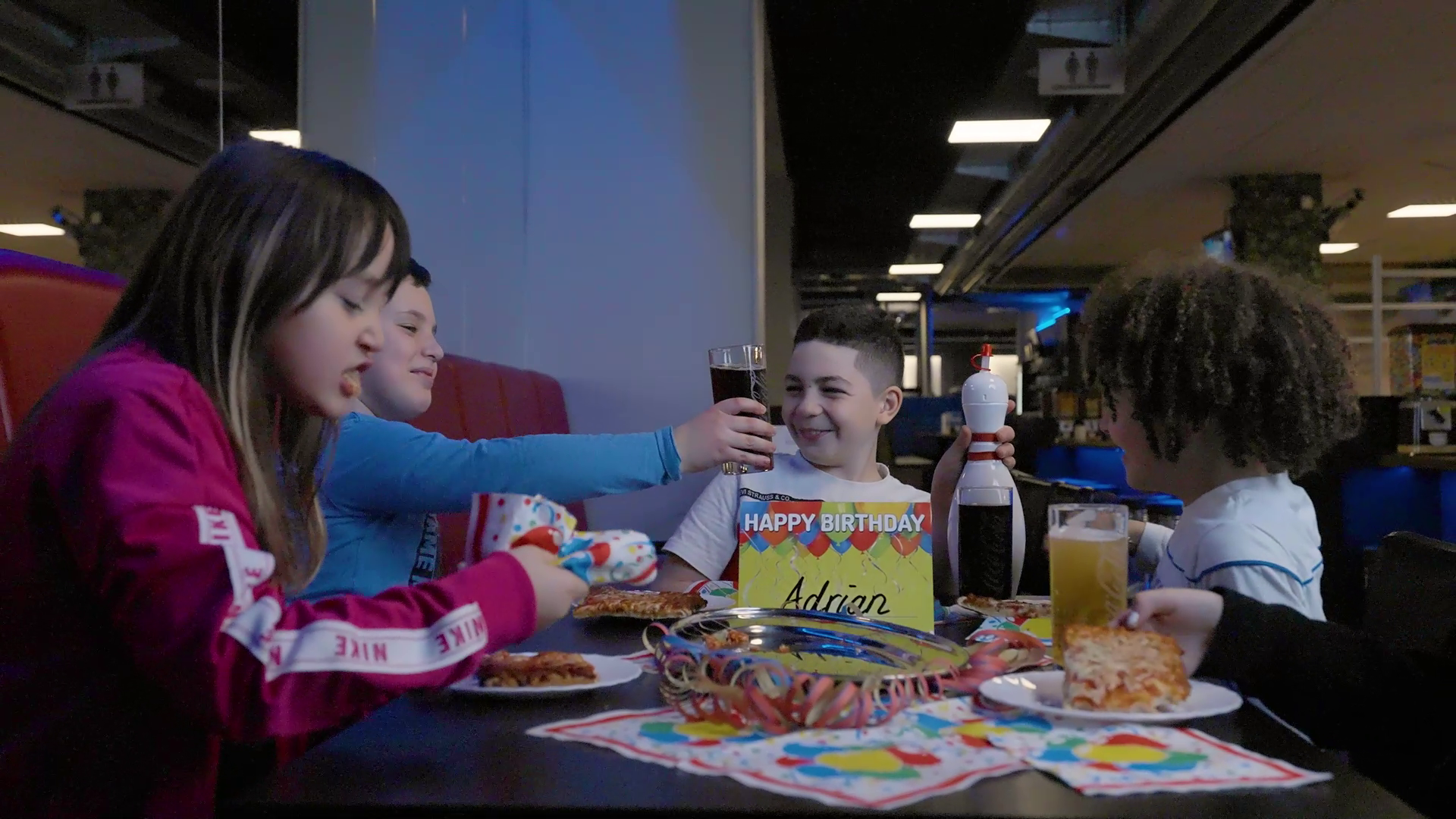 Bild Kindergeburtstag mit Kindern, die zusammen Geburtstag feiern. Mit gedecktem Geburtstagstisch, Getränken und Pizza-Schnitten.