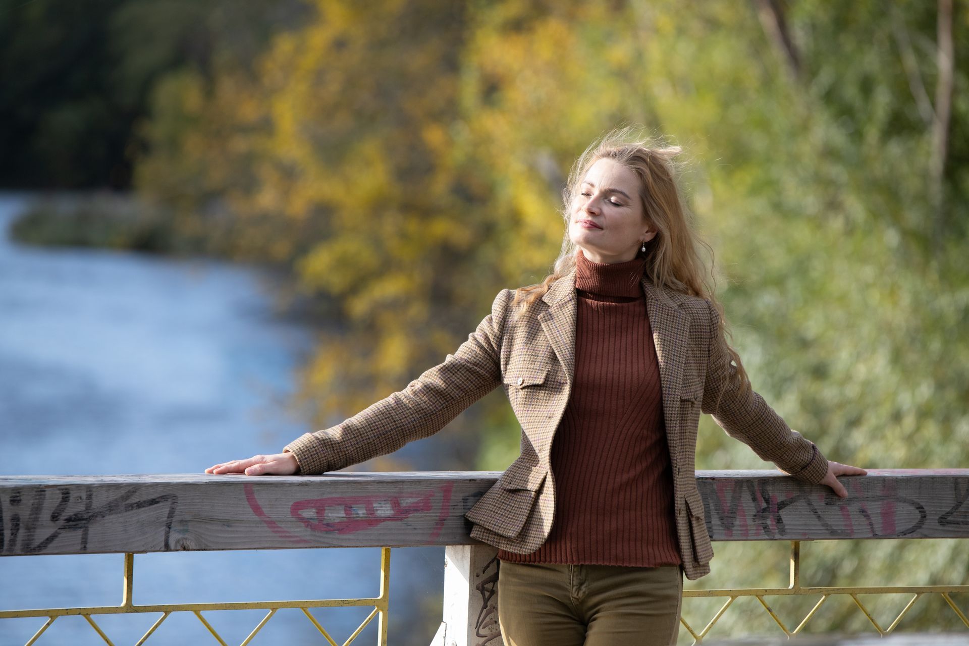 Frau outdoor auf Brücke, Hintergrund herbstlicher Wald und Wasser