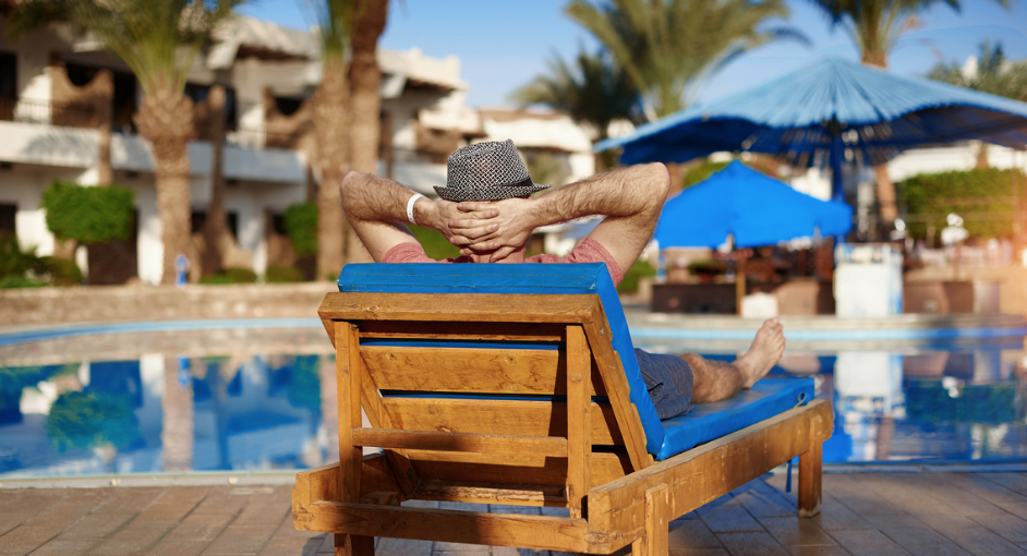 man sitting on a chair next to a pool