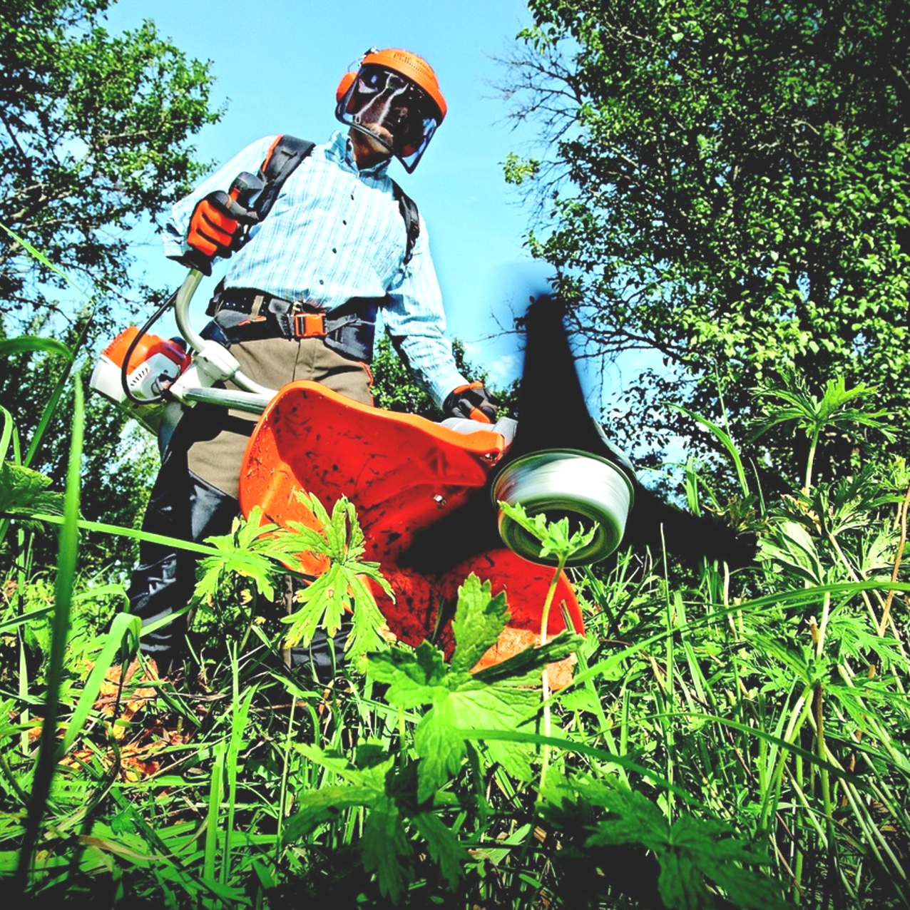 Ein Gartenlandschaftsbauer der das Gras trimmt.