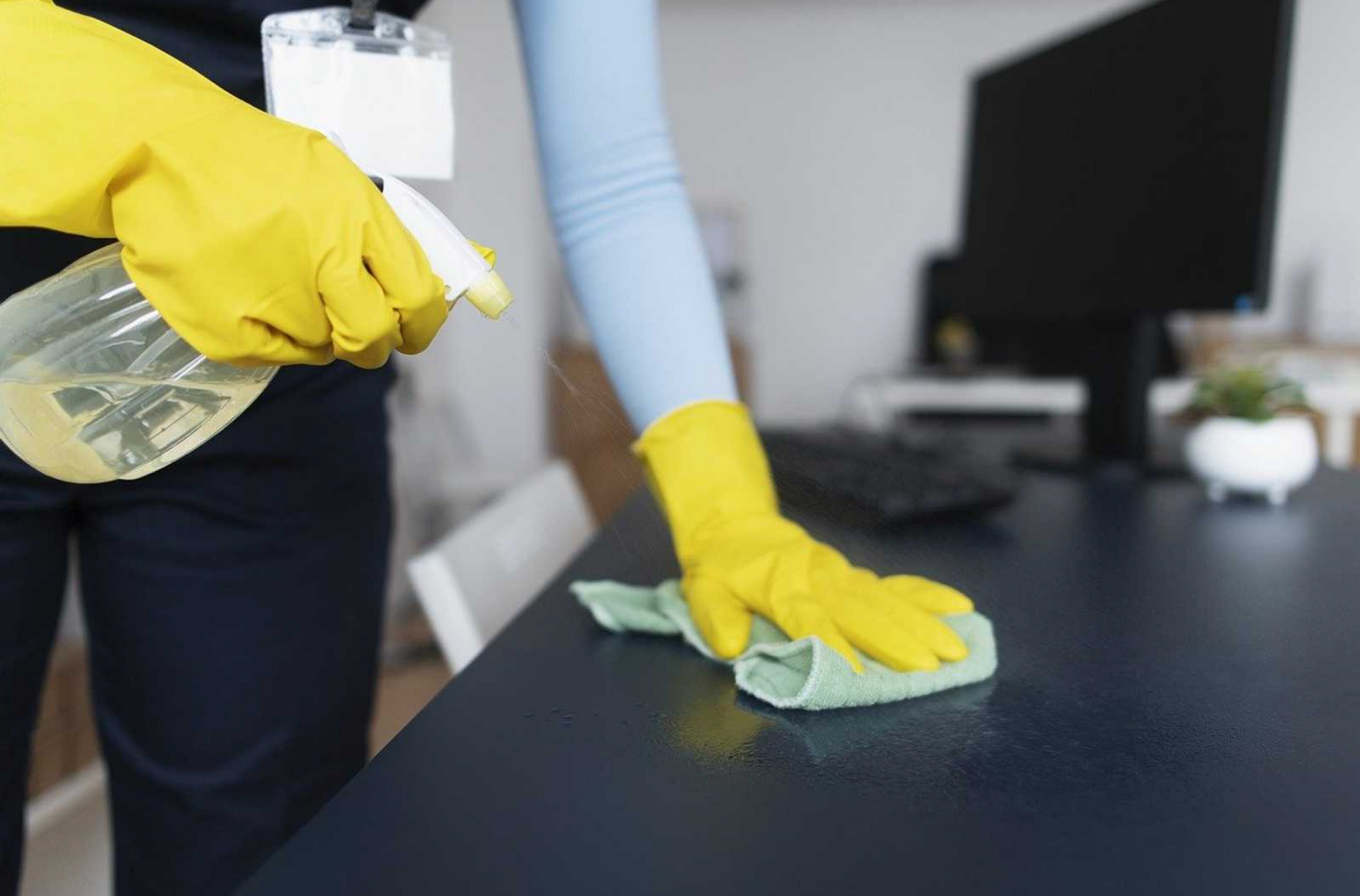 Eine Reinigungskraft die ein Tisch im Büro reinigt