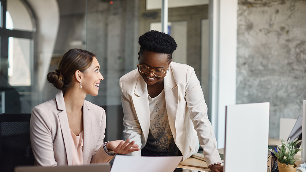 Learn more about our Coordinated Planning & Zoning services Two professional women discussing documents, representing coordinated planning and zoning services.
