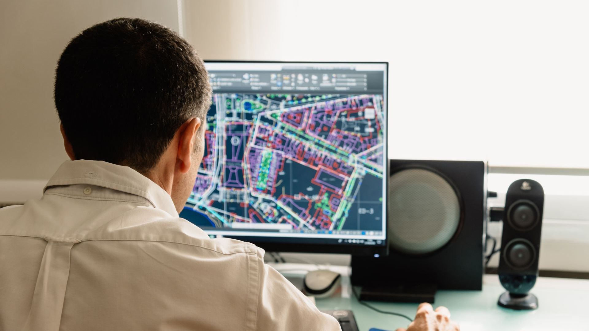 Discover how we use GIS to support mapping, planning, and data-driven decisions. Person analyzing a digital city map on a computer screen, representing GIS services.