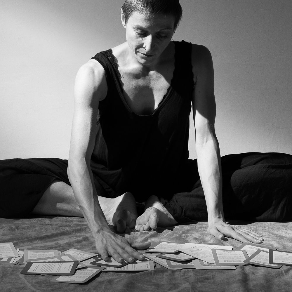 Femme assise sur le sol, qui choisis des cartes posées devant elle.