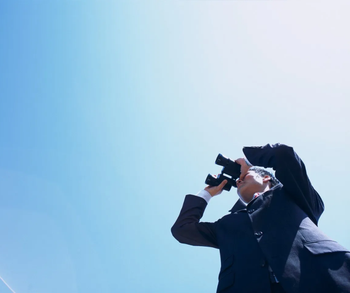 Wir behalten für Sie das Große Ganze im Blick Person blickt mit Fernglas auf den Horizont