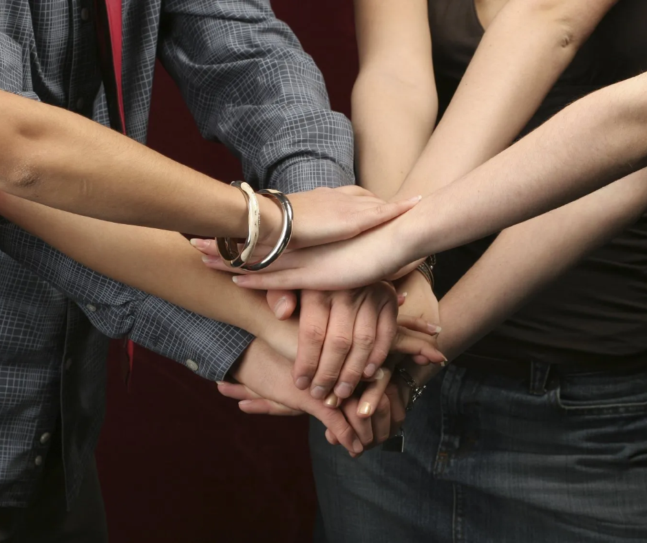 Our focus are people Four people are shaking hands at the same time