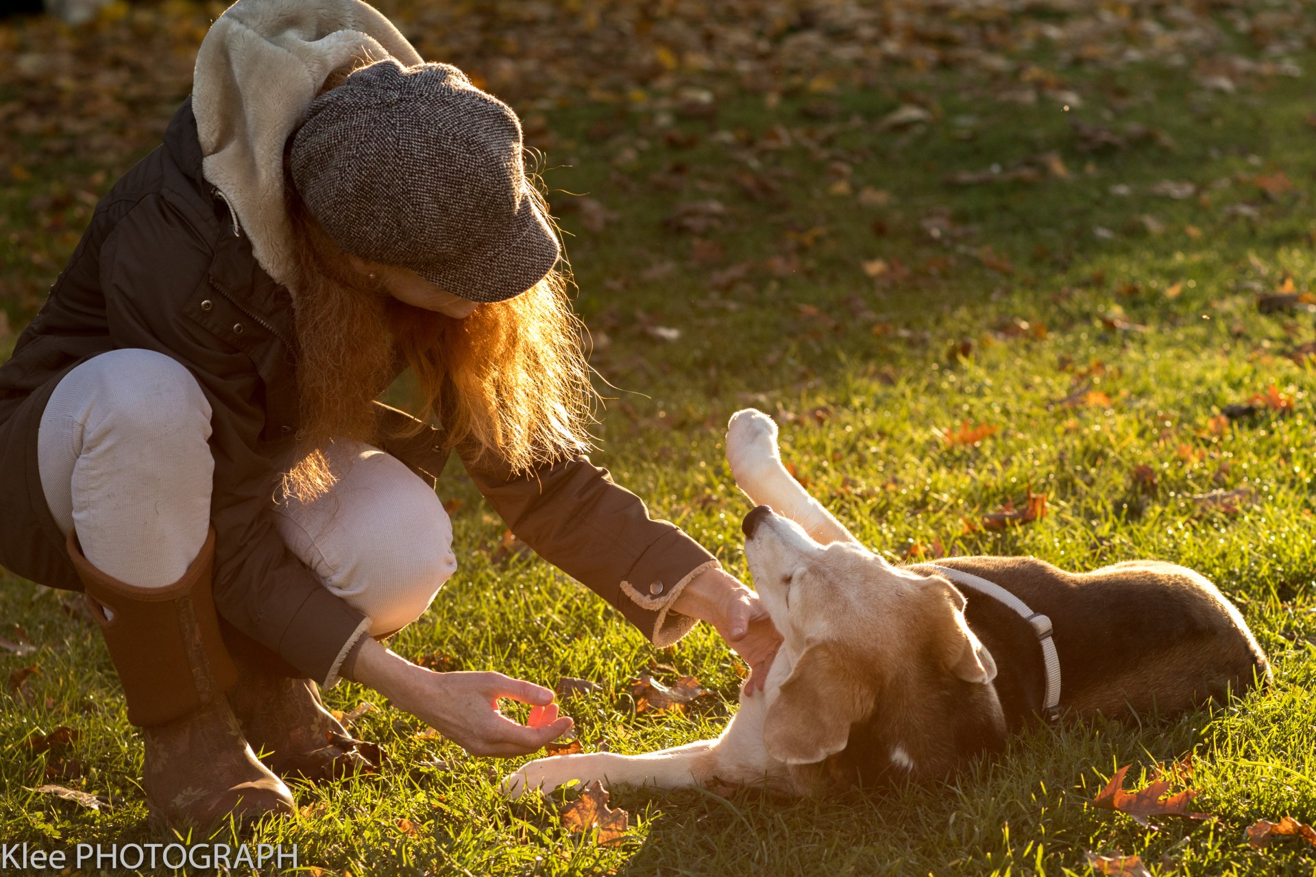 Claudia Fraefel mit einem Hund, der auf dem herbstlichen Rasen liegt und seine Brust präsentiert.