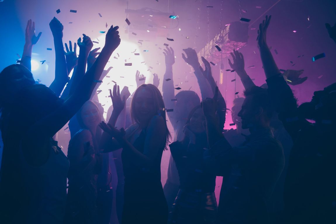 People dancing at a nightclub while confetti falls down.