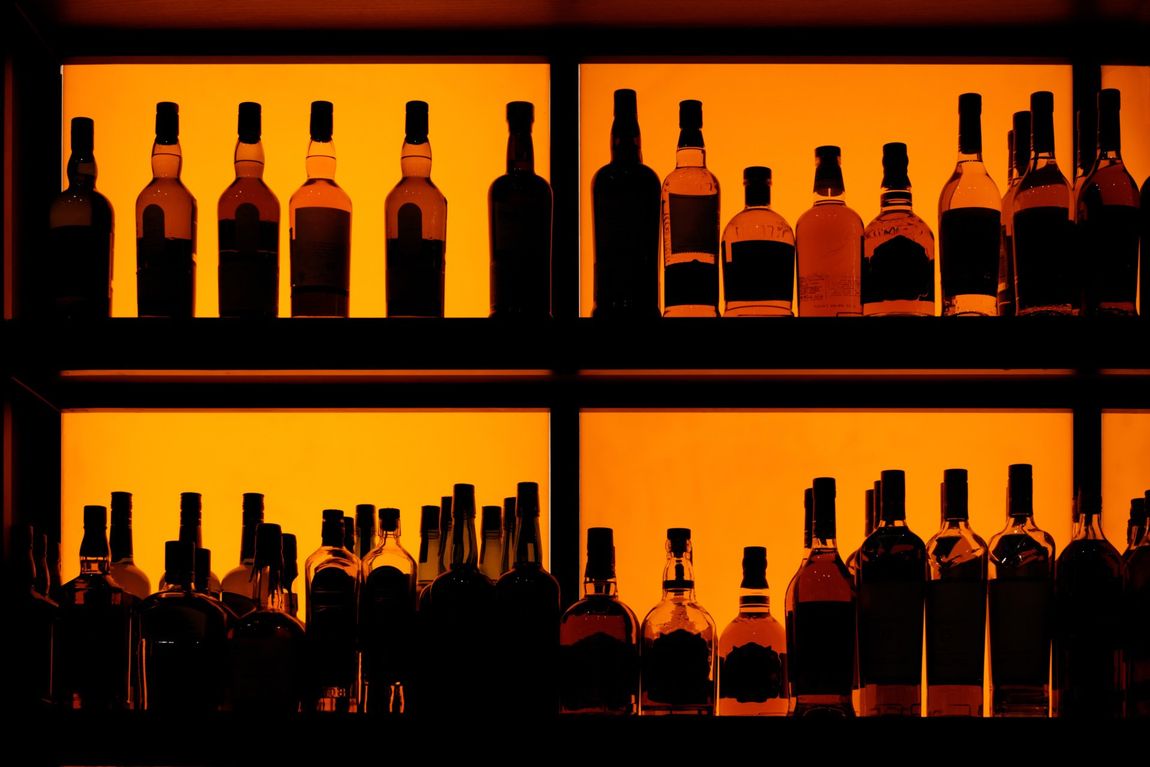 Bottles of alcohol on a backlit shelf in a bar.