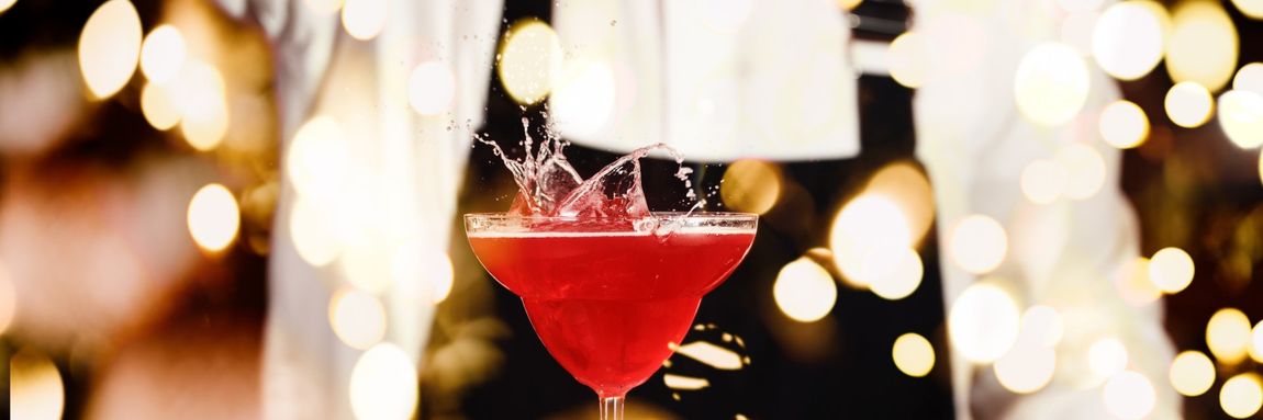 A red drink in a fancy glass splashes.