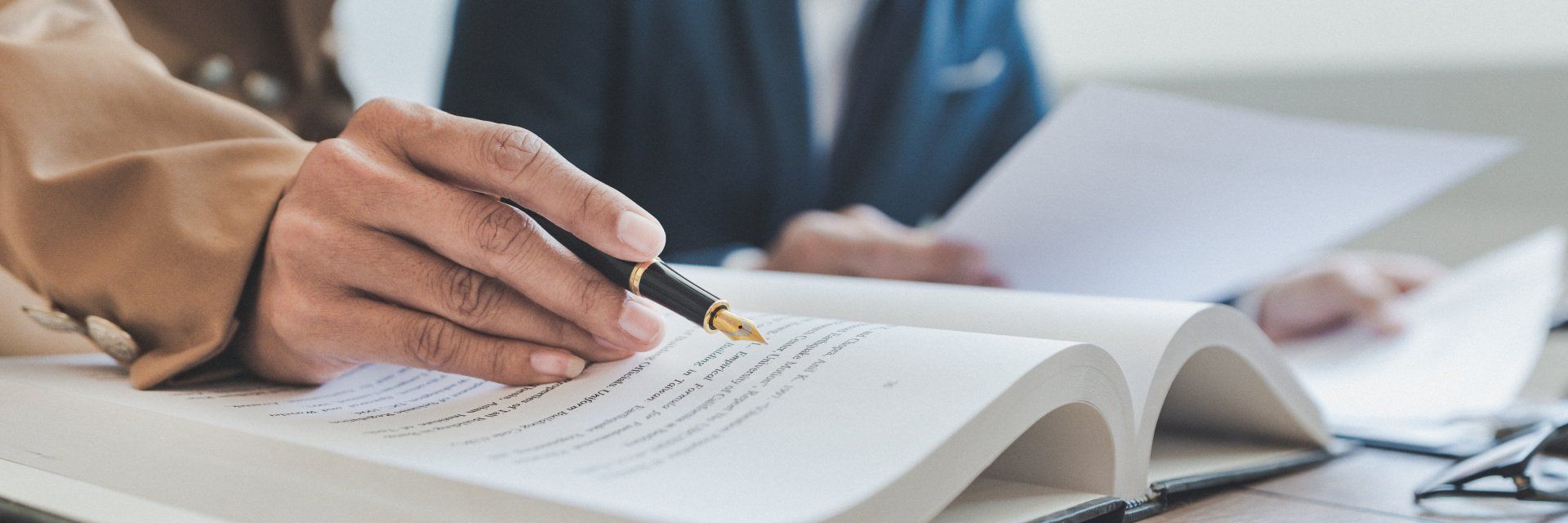 A handholds a pen, noting something in a book.