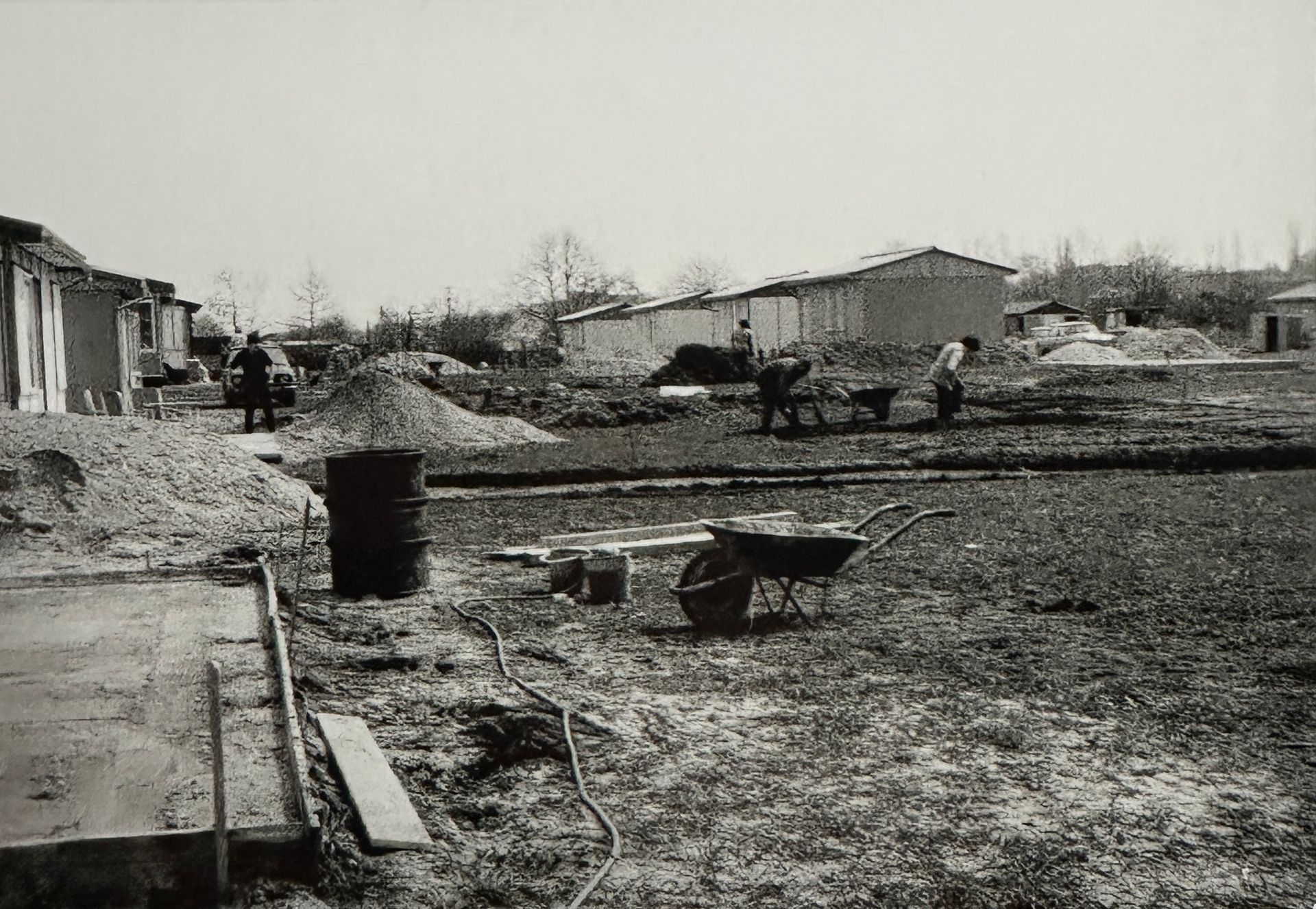 Im Hintergrund stehen schon vereinzelte Lauben. Unten links sieht man eine gegossene Bodenplatte. Viel freie Rasenfläche