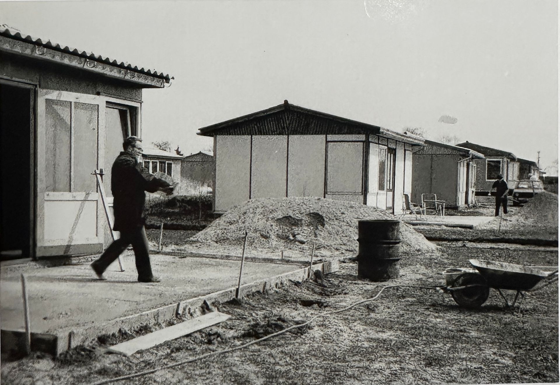 Mann steht auf Bodenplatte der Terasse seiner Laube. Im Hintergrund ist eine weitere fertige Laube zu sehen.