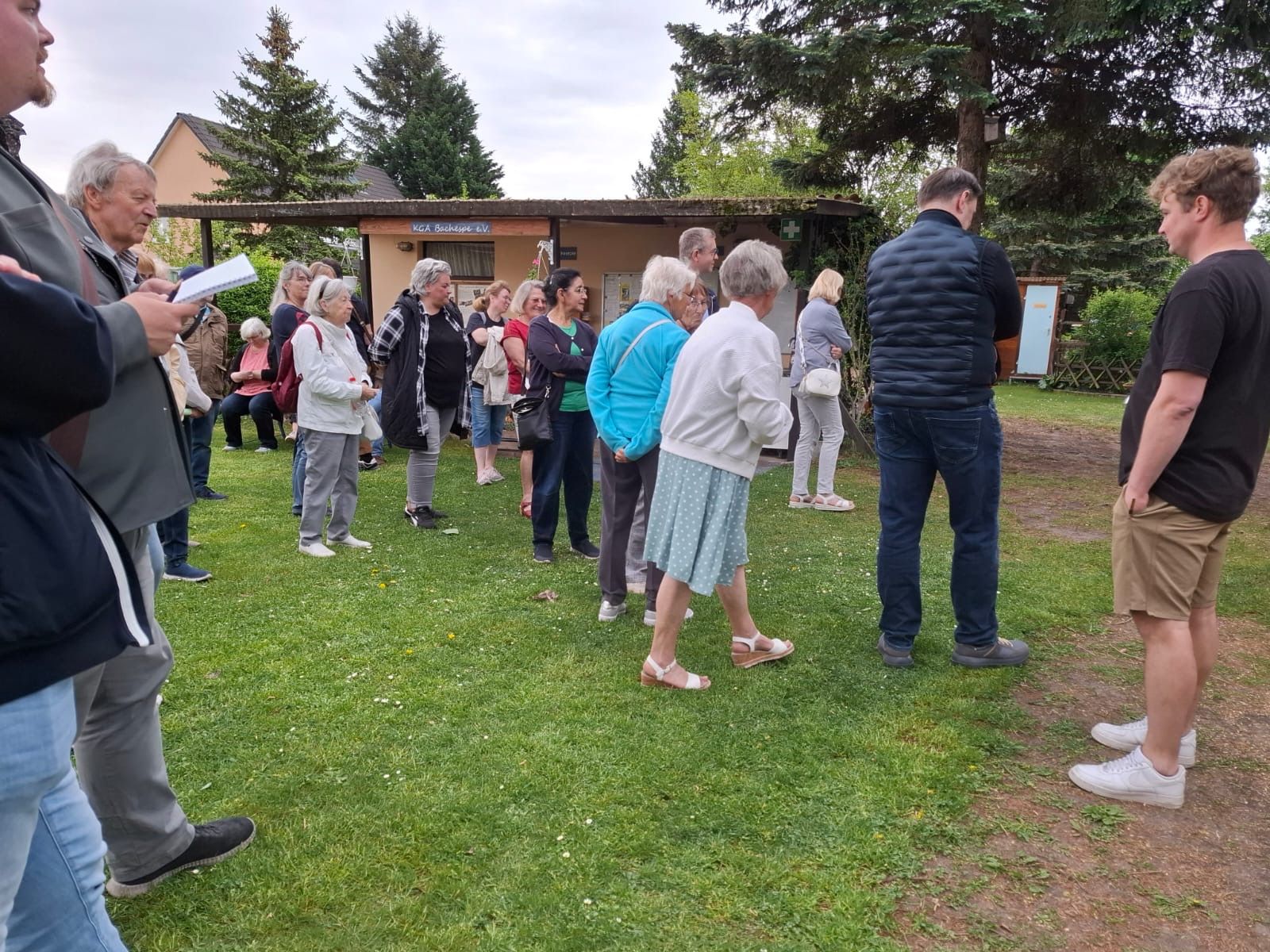 Bild zeigt verschiedene Personen der KGA Bachespe sowie weitere Personen, die im Rahmen des Kiezspazierganges mit Herrn Stefan Evers auf der Festwiese vor dem Pumpemhaus der KGA Bachespe stehen.
