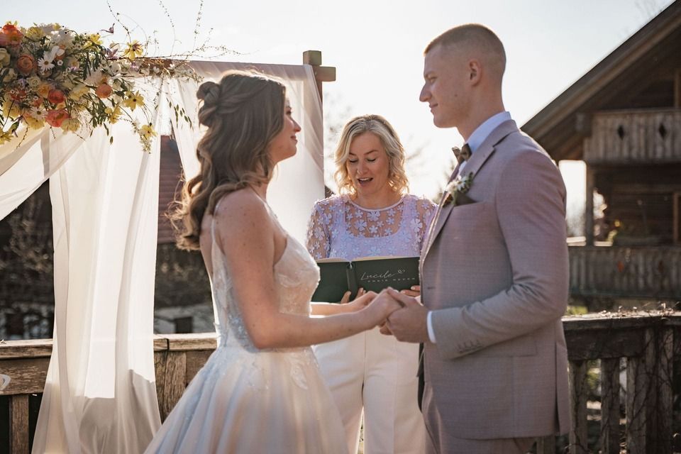 Lucile bei einer freien Trauung: in der Hand die Rednermappe, vor ihr das lächelnde Brautpaar.