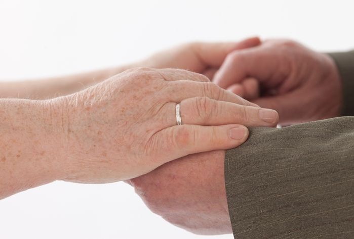 Faltige Hände eines Paares, das viele Jahre miteinander durchlebt hat und durch einen erneuten Ringtausch seine Liebe feiert.