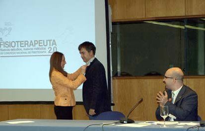 Antonia Gómez Conesa, presidenta de la AEF, hace entrega de la insignia a Miguel Ángel Alcocer Ojeda, director de Fisiomechanics