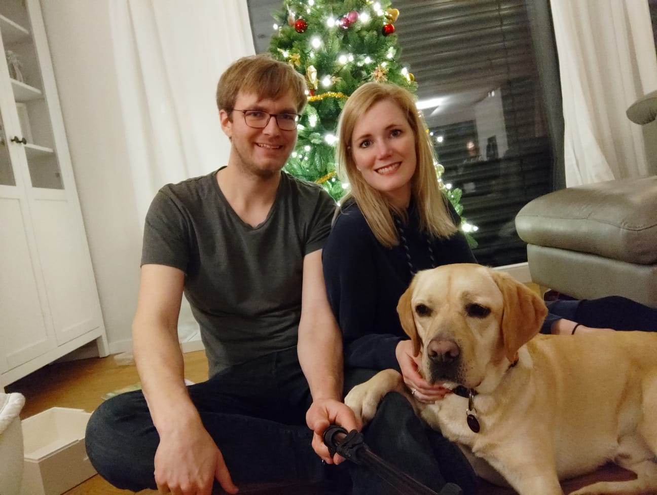 Finnley mit den Eltern der Familie am Boden sitzend kuscheln vor dem Christbaum