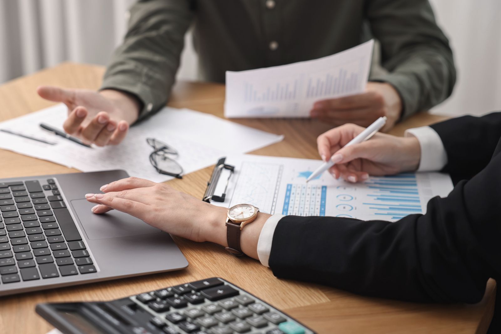 Consultant working with client at wooden table in office, closeup. Business meeting