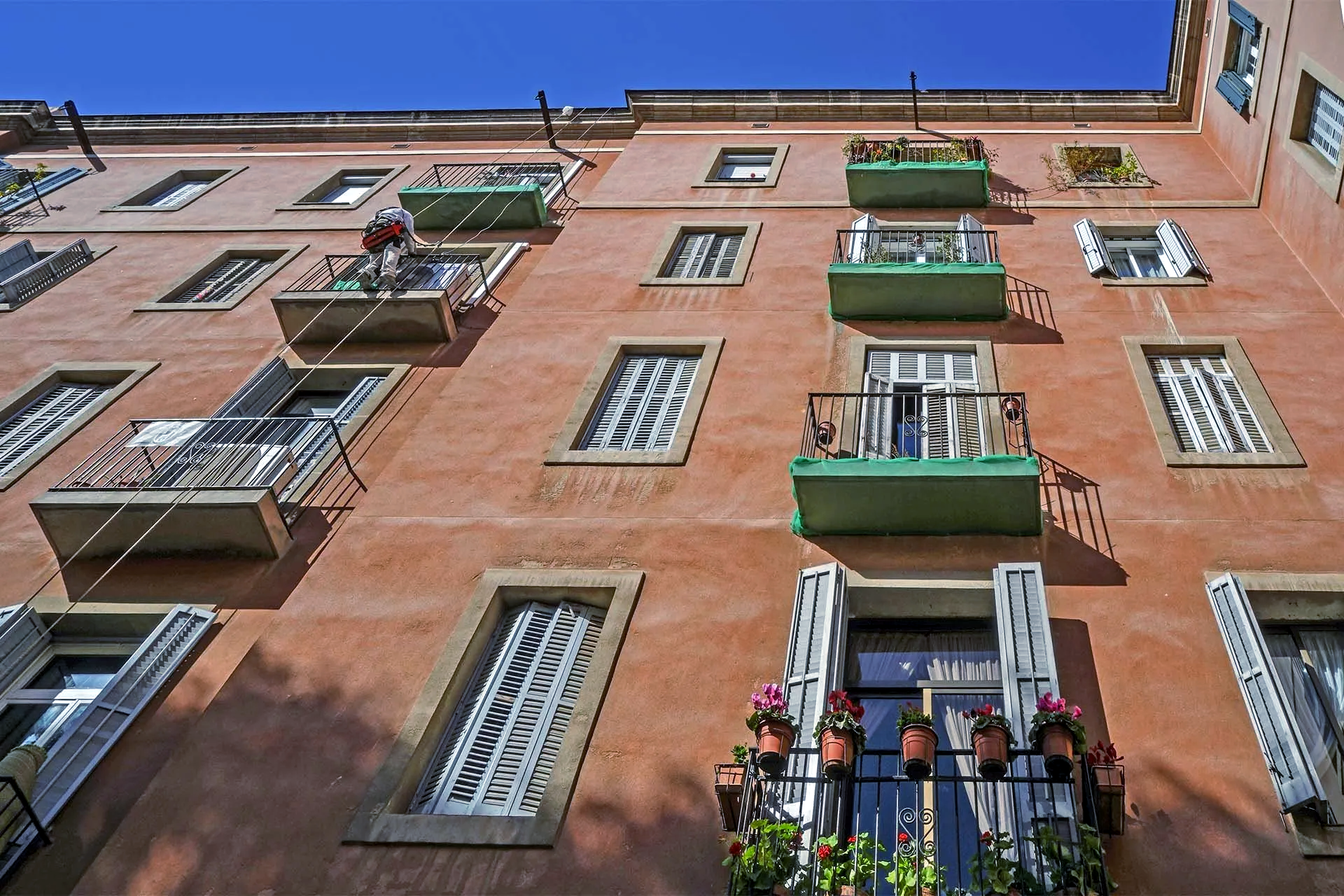 Perspectiva exterior frontal punto hacia el cielo, donde se aprecia el paramento vertical restaurado, con operario en andamio descolgado sobre la fachada