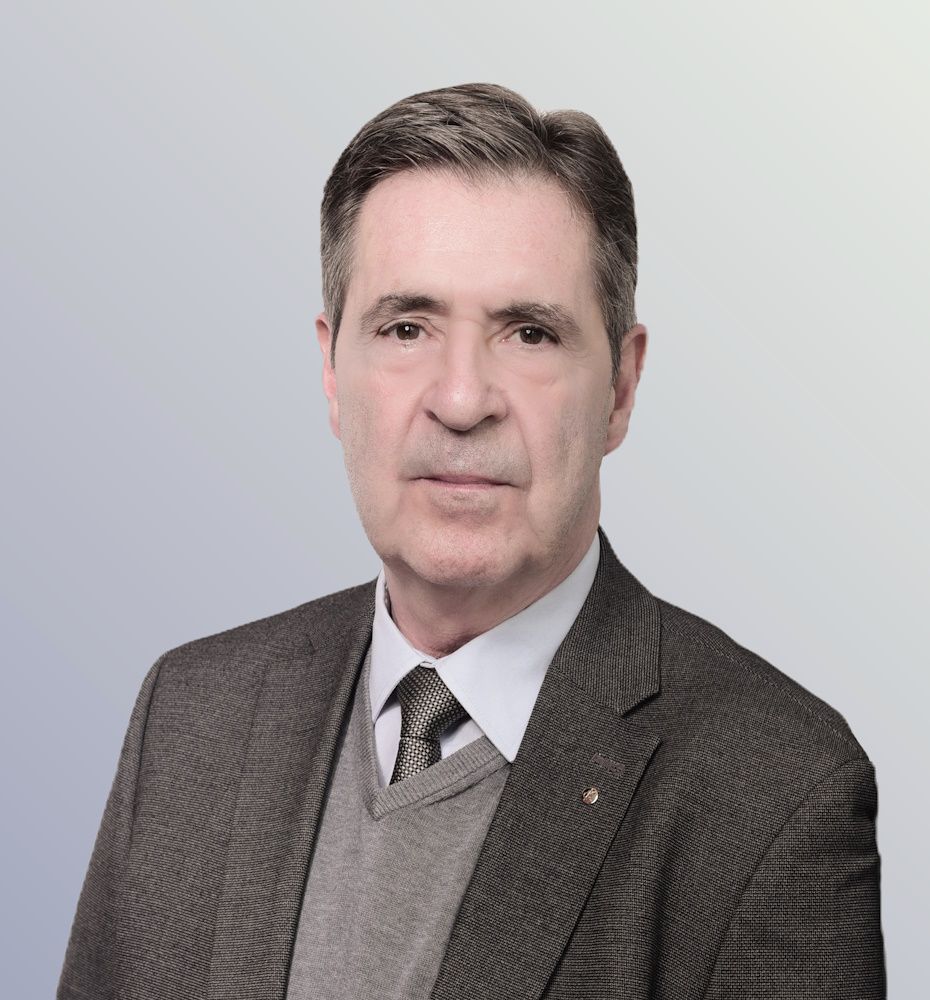 Stefan Hermann Schuster Rechtsanwalt Stefan Hermann Schuster, dunkle Haare, graues Jackett, weißes Hemd, weiße Krawatte, die Arme vor sich verschränkt.. Hintergrund weiß mit stilisierter Skyline von Frankfurt, Commerzbanktower..