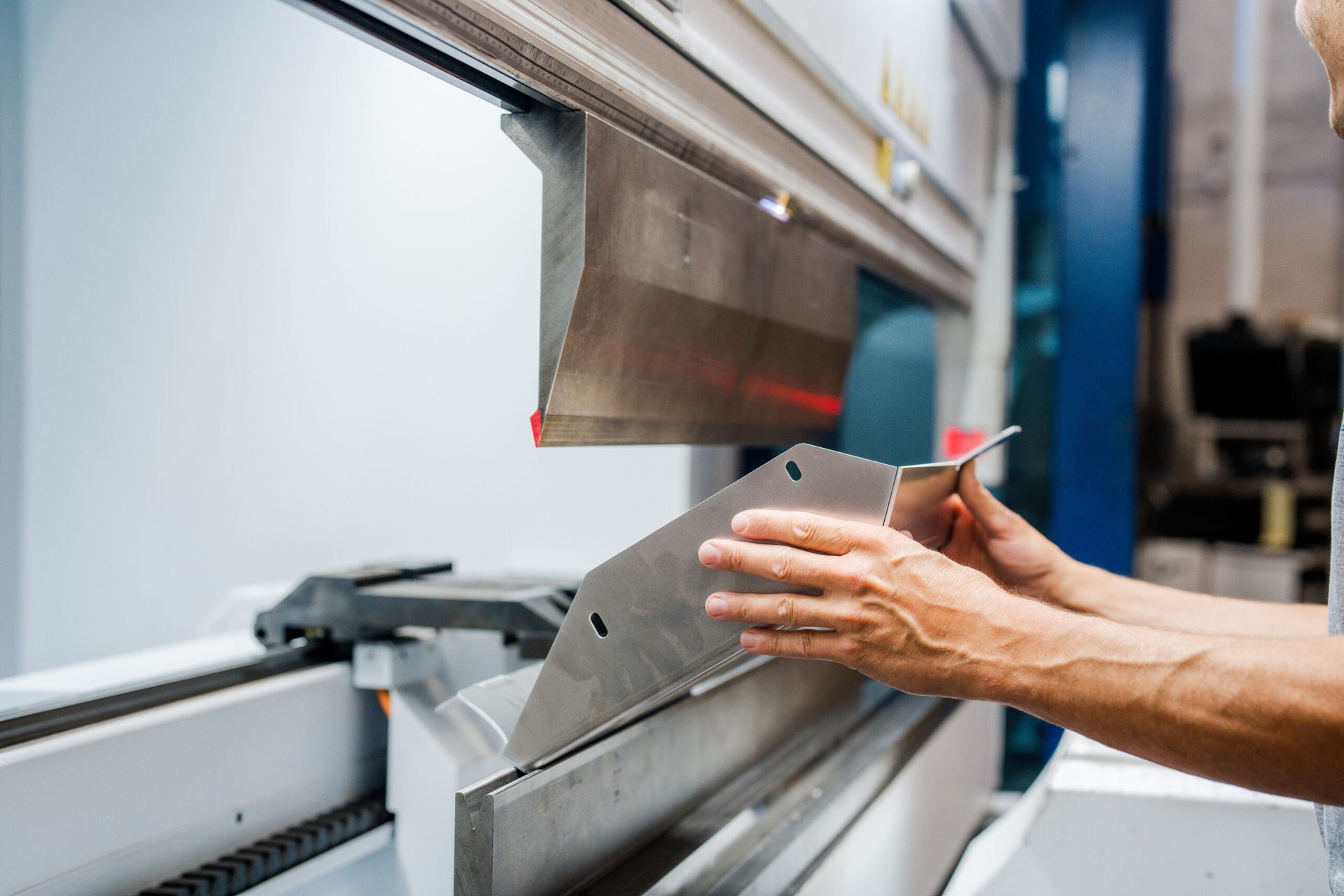 Ein Arbeiter hält ein Blech in eine Abkantmaschine.
