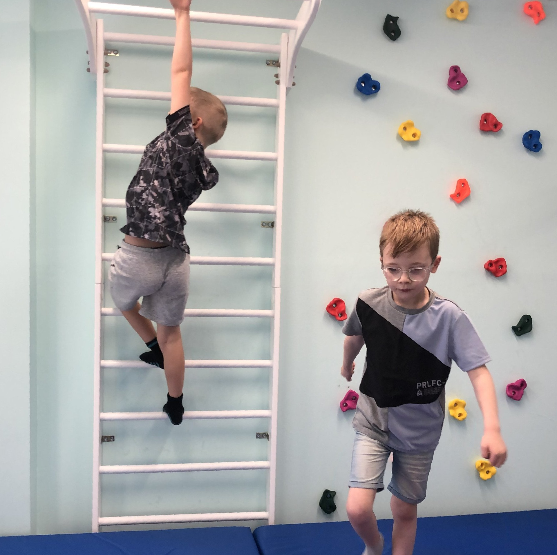 Child climbing Swedish ladders in wall climbing area of Smart Gym creche in Pollok