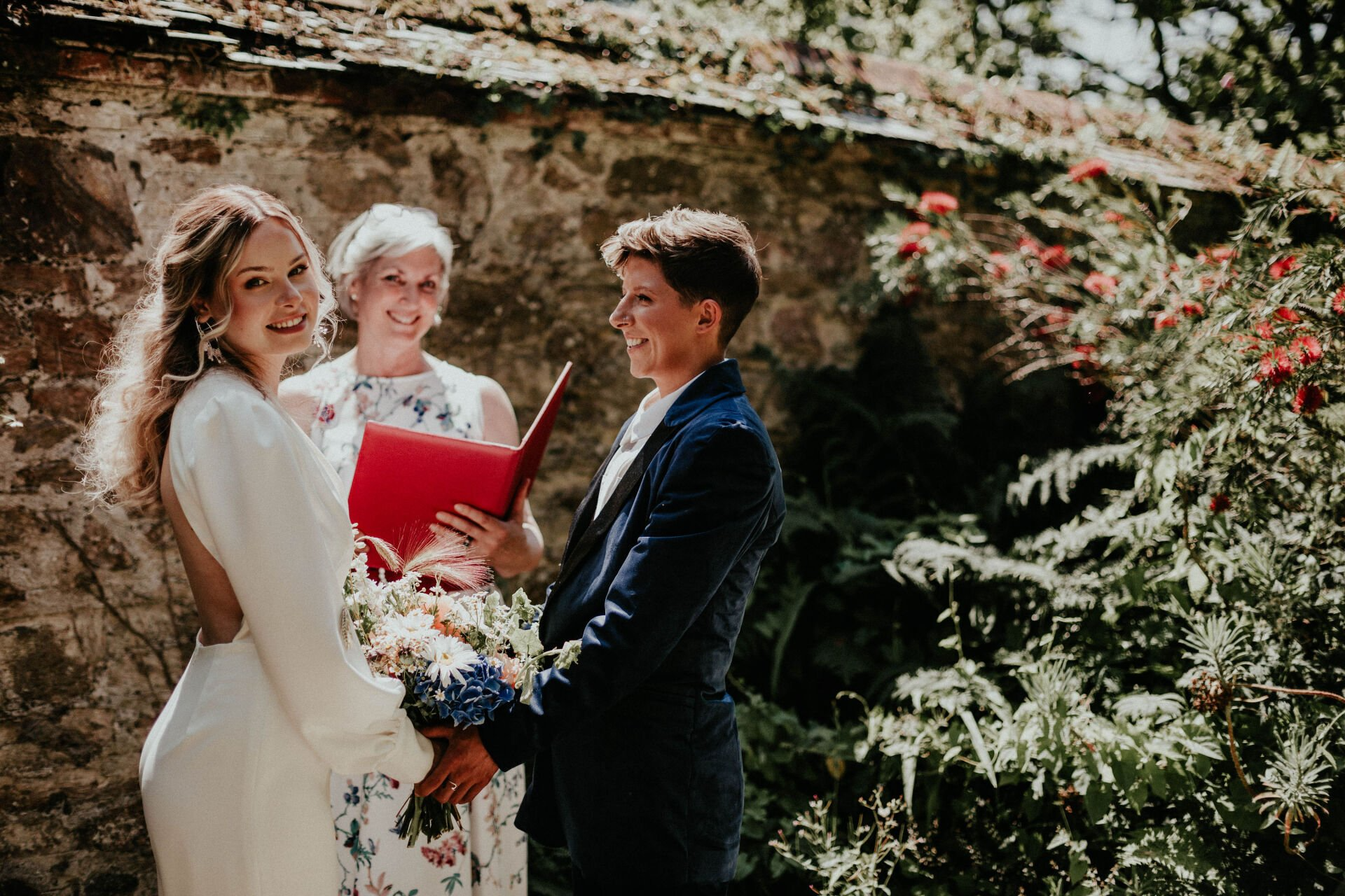Sara Price Celebrant  with bride and bride during a garden wedding ceremony