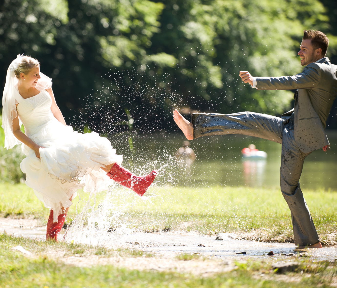 bride and groom kicking water at each other and laughing
