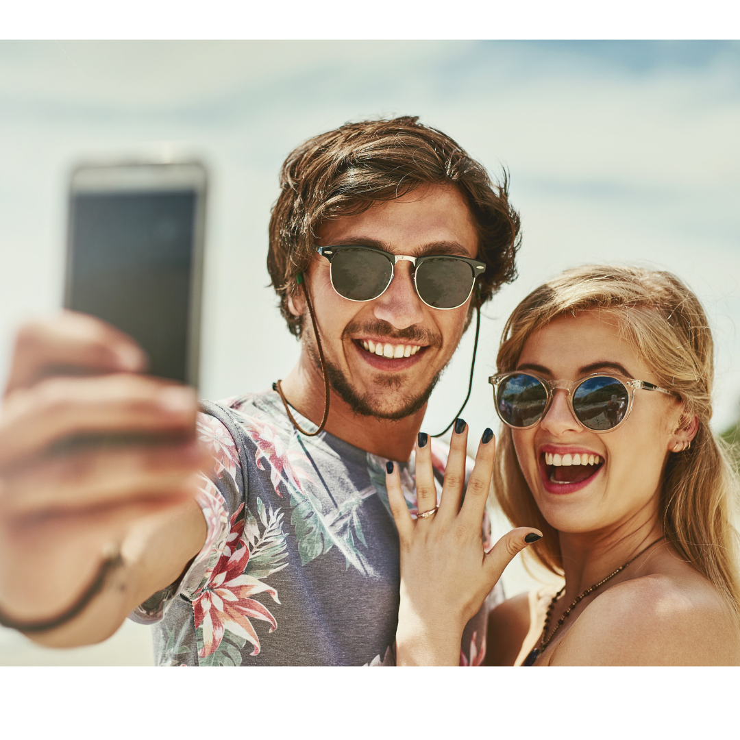 newly engaged young couple taking selfie showing off ring