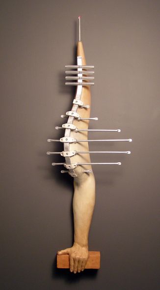 ceramic and aluminum, 54 A human arm, augmented with TV antennas, supported in a brick.