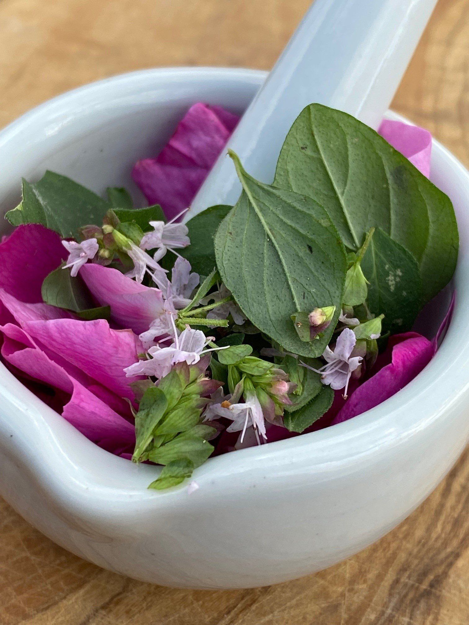 Verschiedene Blüten und Kräuter im Porzellanmörser