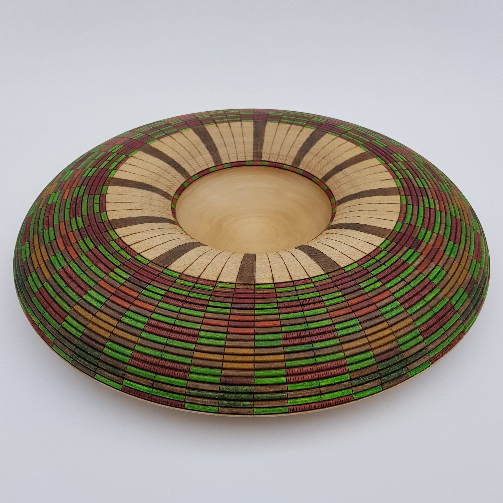 Basket weave illusion Large wood turned bowl with donut ring shaped rim decorated with a basket weave illusion effect. Coloured with greens, browns, reds and oranges of Autumn leaves. Undecorated wood in the centre.