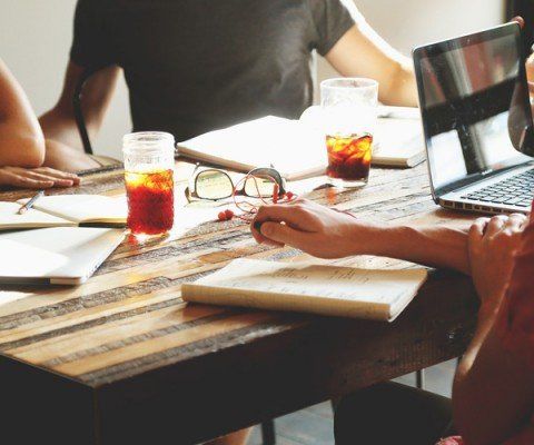 people sitting around a table working on laptop and writing notes